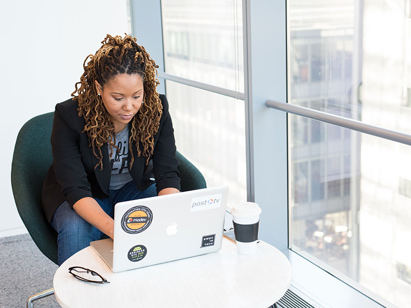A Black women typing on a laptop