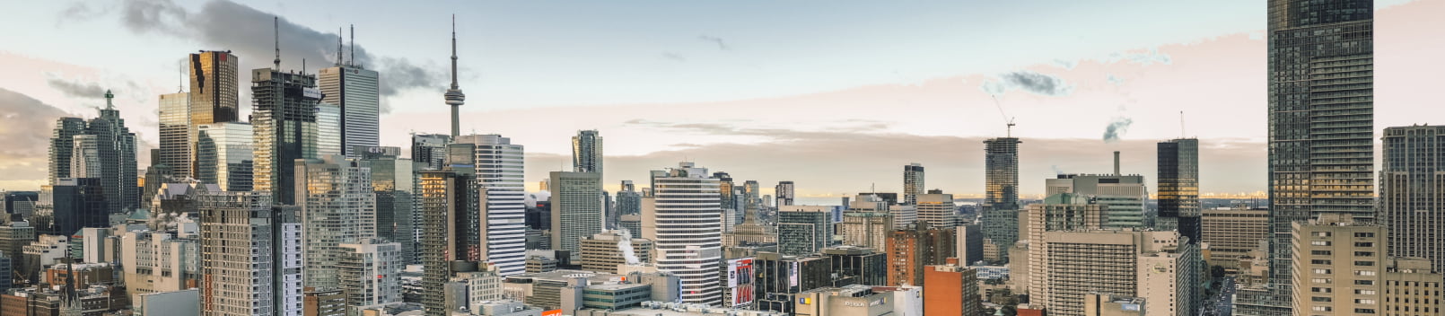 Panoramic high-angle view of the downtown Toronto skyline, featuring the CN Tower and surrounding high-rise buildings.