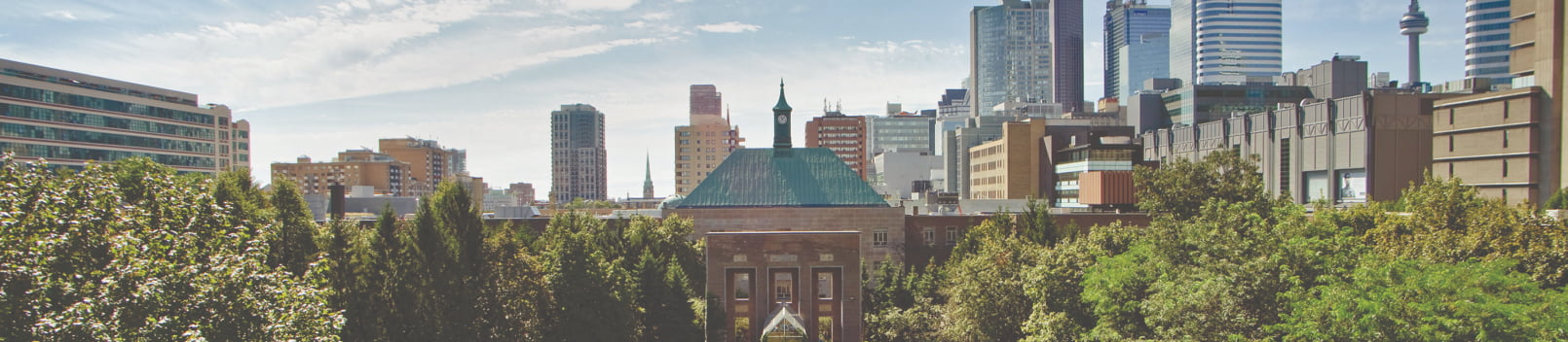 Wide view of the TMU campus quad and historic Kerr Hall building, framed by green trees with downtown Toronto skyscrapers in the background.