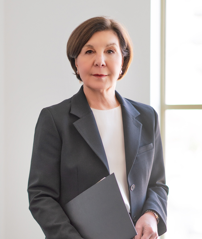 Portrait of The Honourable Mary Lou Benotto in a blazer, holding a document.