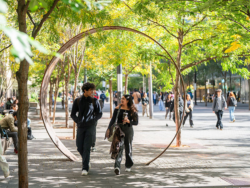 Two students walk through The Ring, an Indigenous art installation that encourages interaction with the artwork.