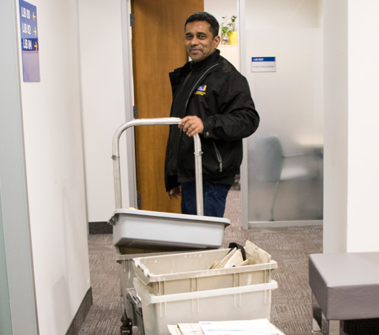 A shipping and receiving worker pulling a cart filled with boxes.