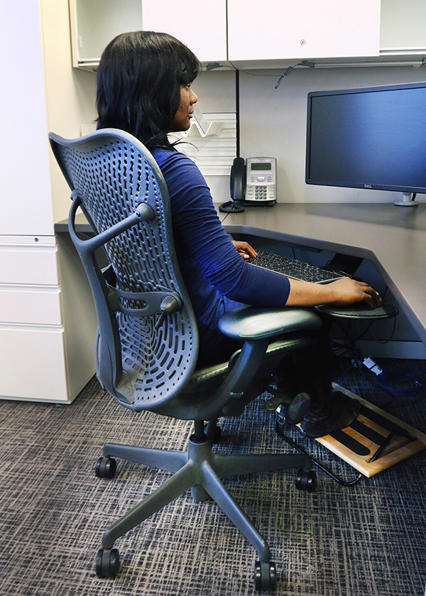 A woman sitting at an ergonomic workstation.