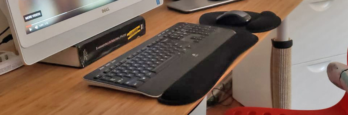 A keyboard and mouse on a desk, both with wristpads for ergonomic use.