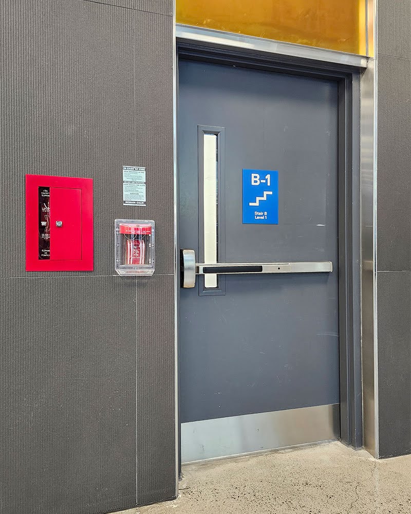 Emergency exit stairwells is behind a closed fire resistant door with an alpha-numeric sign that identifies the stairwell and the floor number.