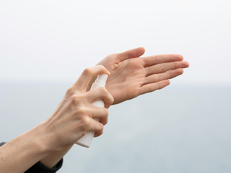 Close up of hands spraying fragranced sanitizer in office