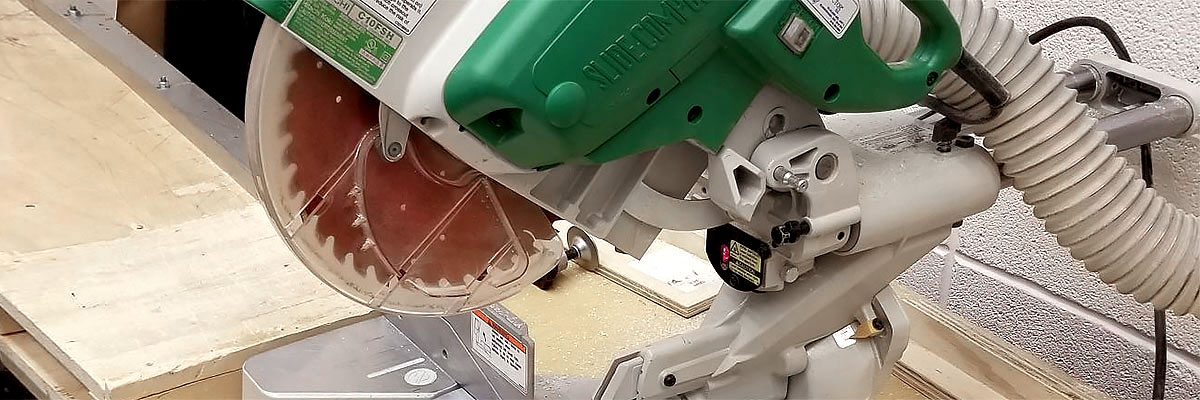 A close-up of a chop saw with its circular blade within a machine guard to reduce the risk of injury.