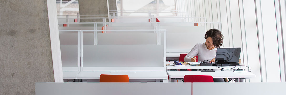 A young woman with a laptop works in solitude at the SLC.