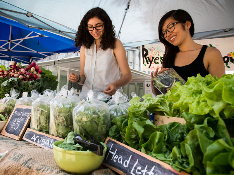 Two women selling food at the university Farmer's Market.