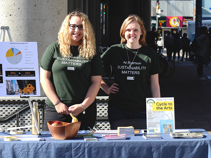 Two volunteers at a sustainability info table.