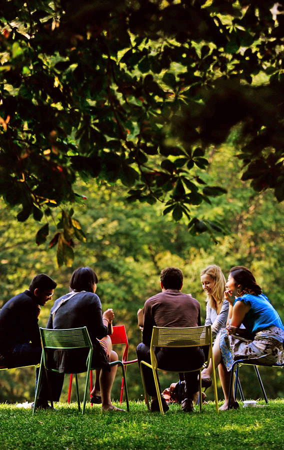 Five students sitting in a circle on chairs in the Quad having a conversation.