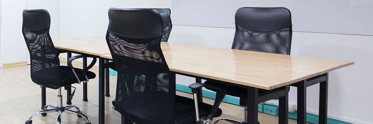 Four black office chairs around a meeting table.