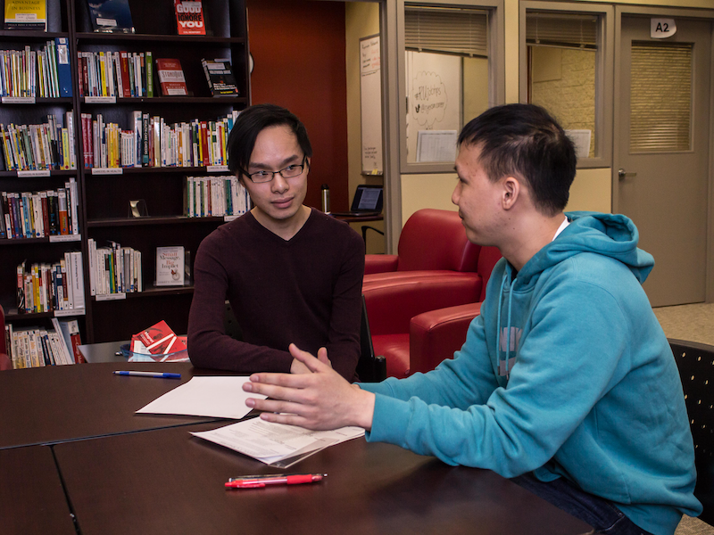 Two students working together at a table in the library