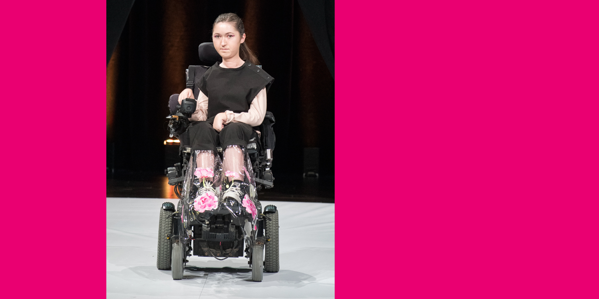 A model on a wheelchair wearing a UN•FORM black dress with clear plastic bottom finishing designed by Fashion Design Alumna, Sonia Prancho.
