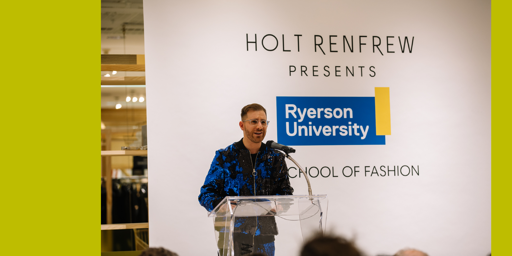 Dr. Ben Barry at the podium at Awards Night with a backdrop that reads "Holt Renfrew presents Ryerson University School of Fashion"
