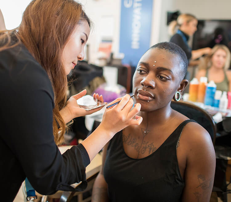 Student doing a model's makeup before a fashion show event