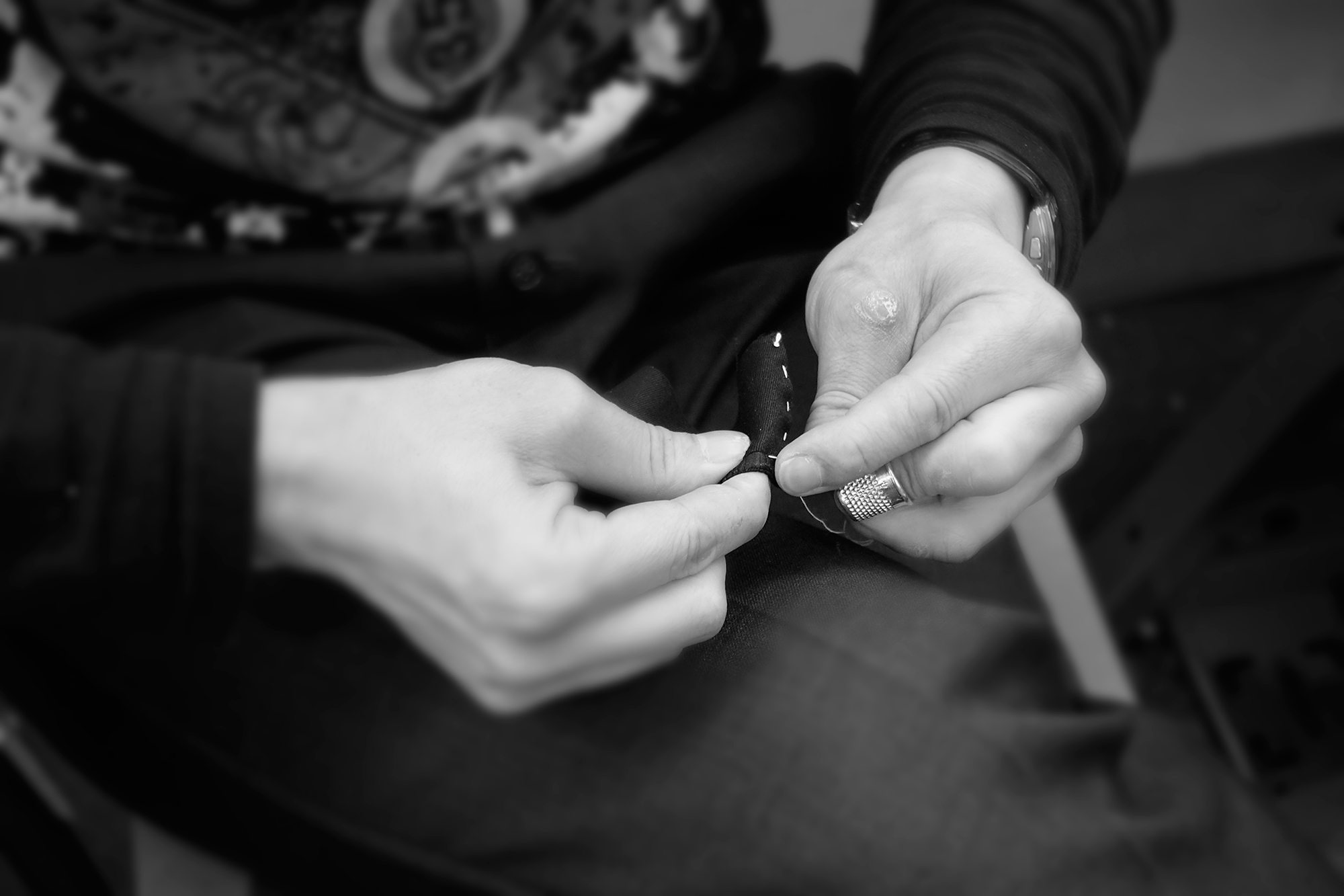 Associate Professor, Robert Ott holding a needle and thread while meticulously tailoring