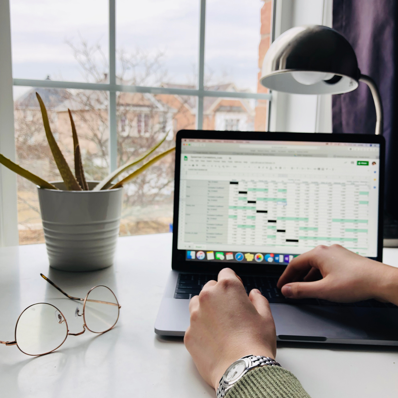 An image capturing the essentials of a graduate school student who's research focuses on quantitative analysis, a laptop with data with a view outside there window