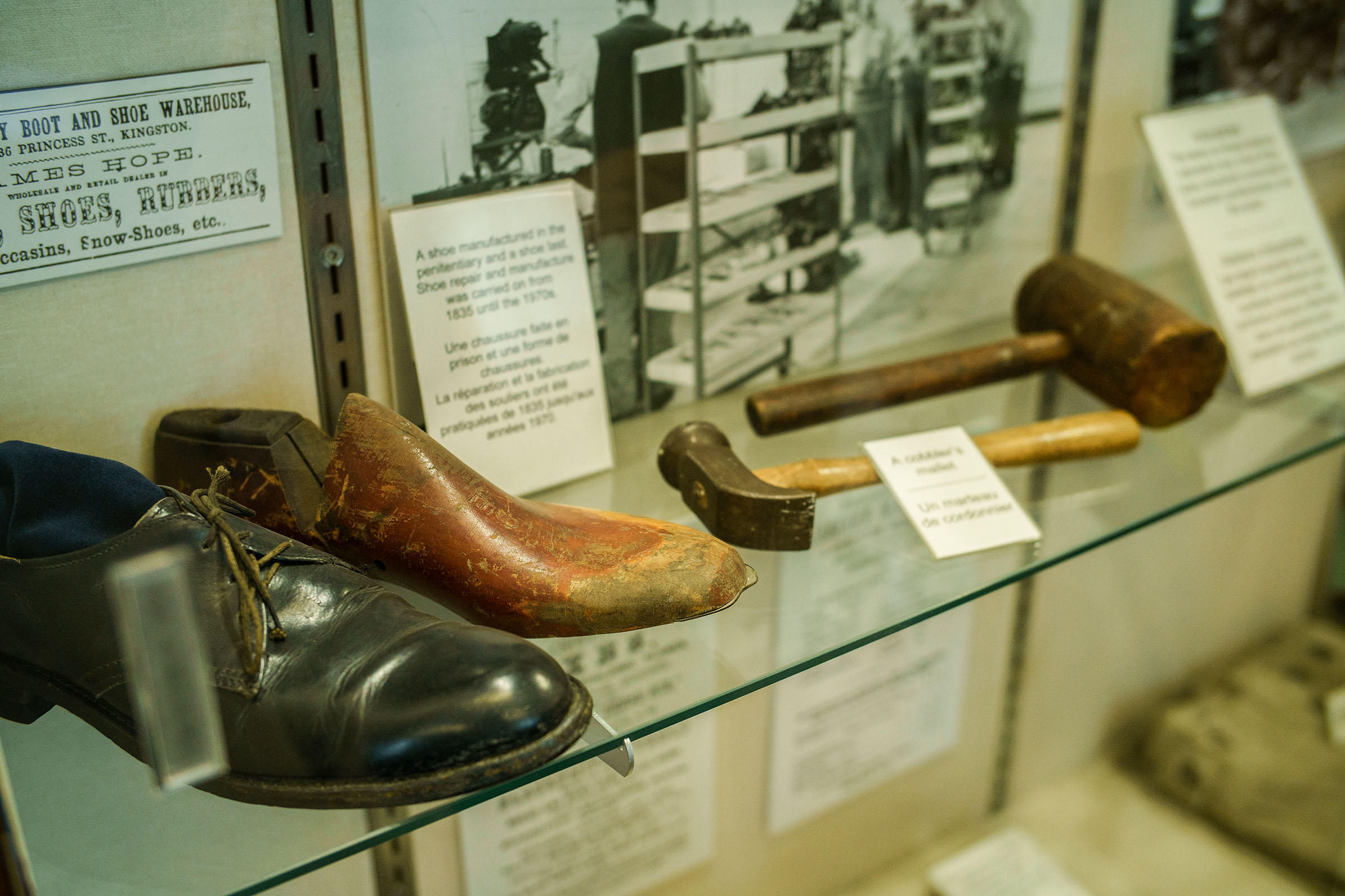 Close up of two shoes, two hammers and two photos in a glass case