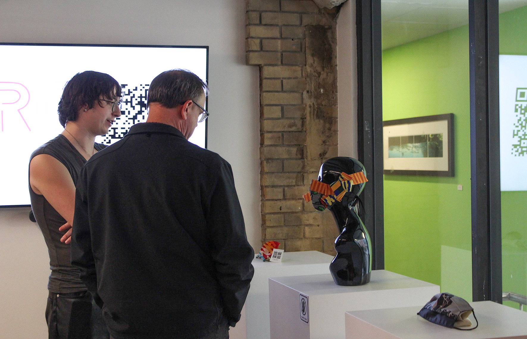 Two people looking at three COVID-19 face masks 