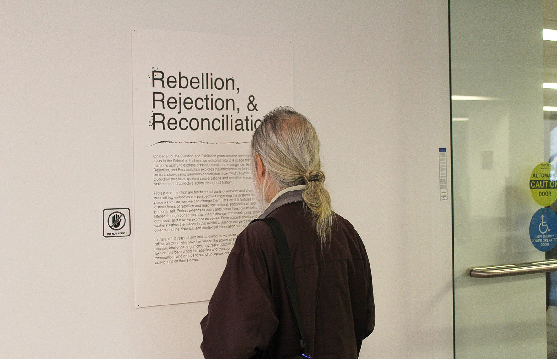 Back of a persons head looking at the main exhibition text for ‘Rebellion, Rejection and Reconciliation’ 