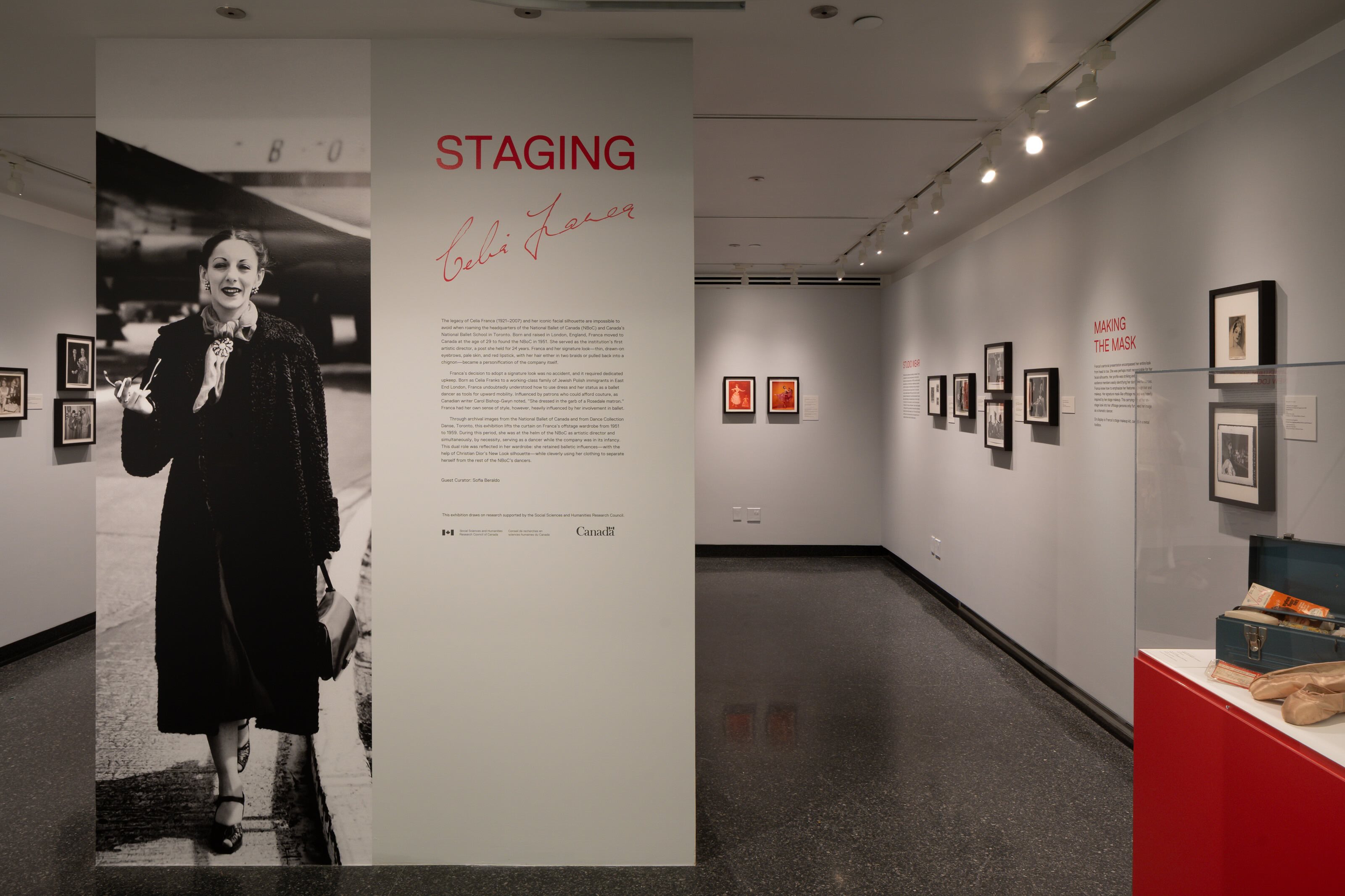 The main text of the exhibition on the left side of the image. The two walls seen to the right have multiple photos mounted on them. 
