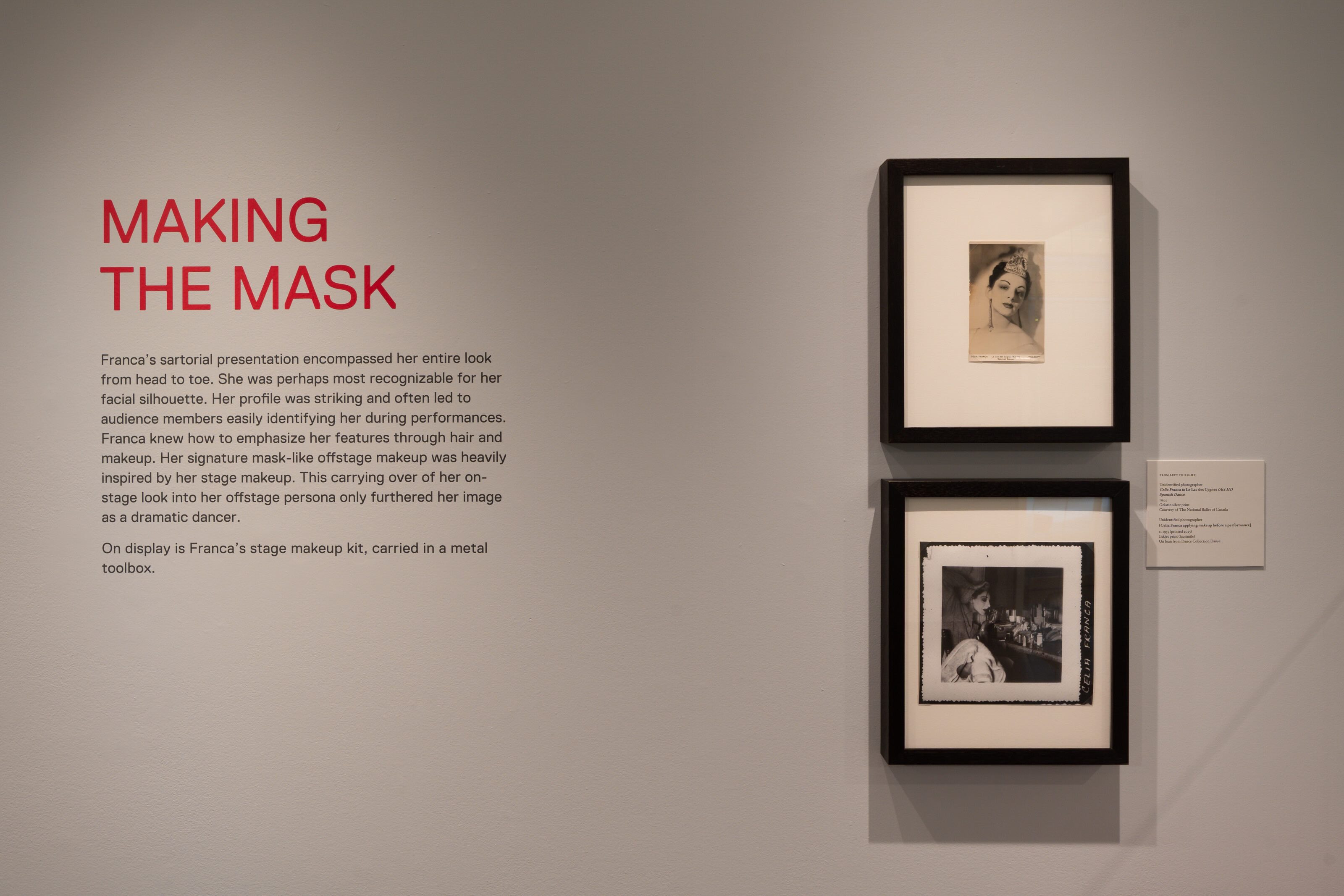 A wall with exhibition text and two photos to the right. Heading reads “Making the Mask” in bright pink text. 