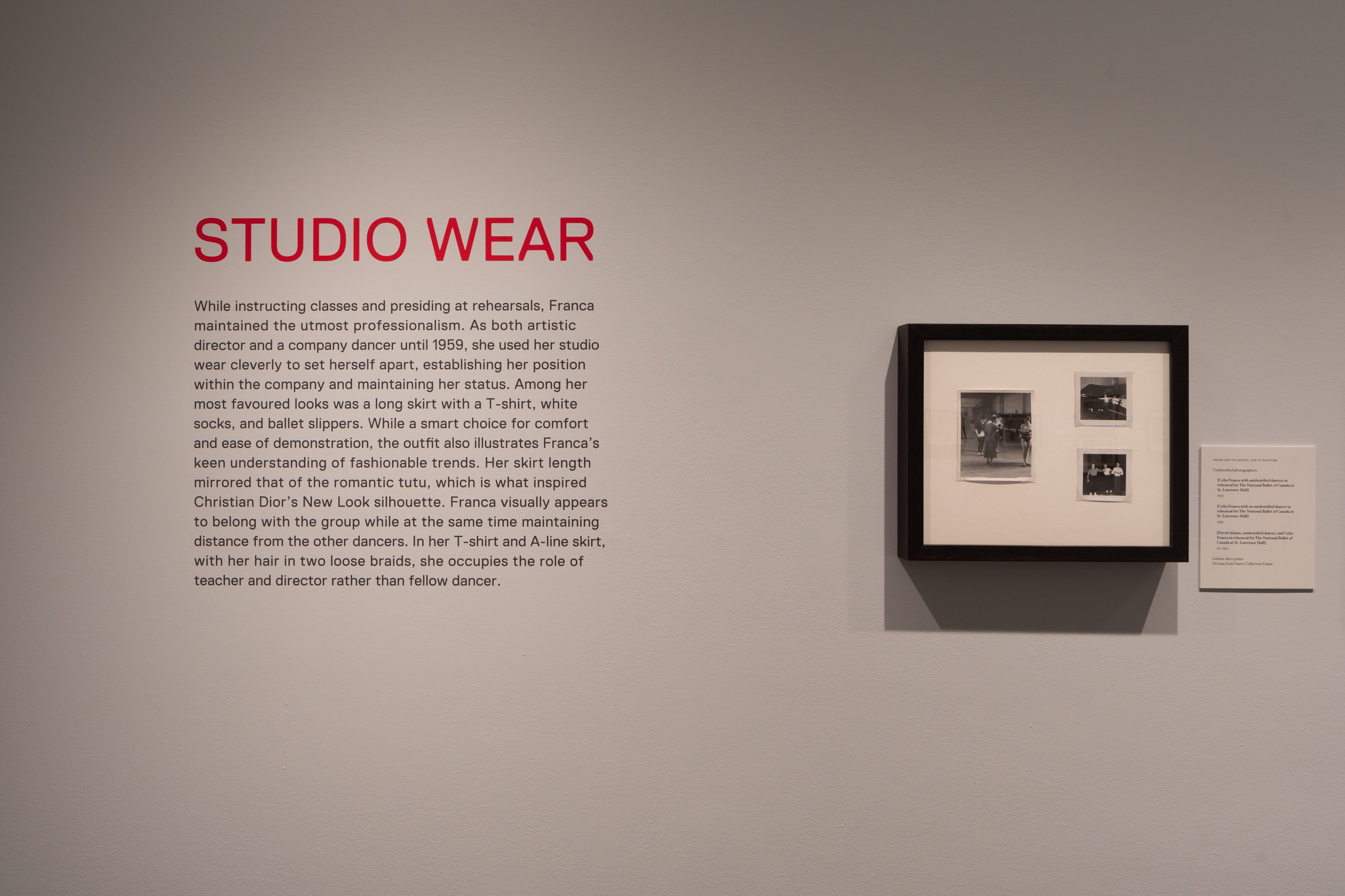 A wall with exhibition text and a photo to the right. Heading reads “Studio Wear” in bright pink text. 