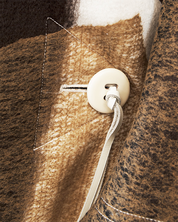 Button and decorative stitching of an Issey Miyake blanket coat