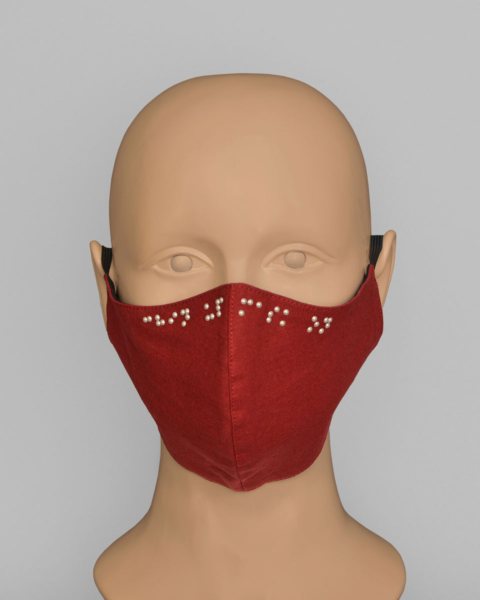 Mannequin head wearing a dark red face mask that reads "Chin Up Mask On" in Braille