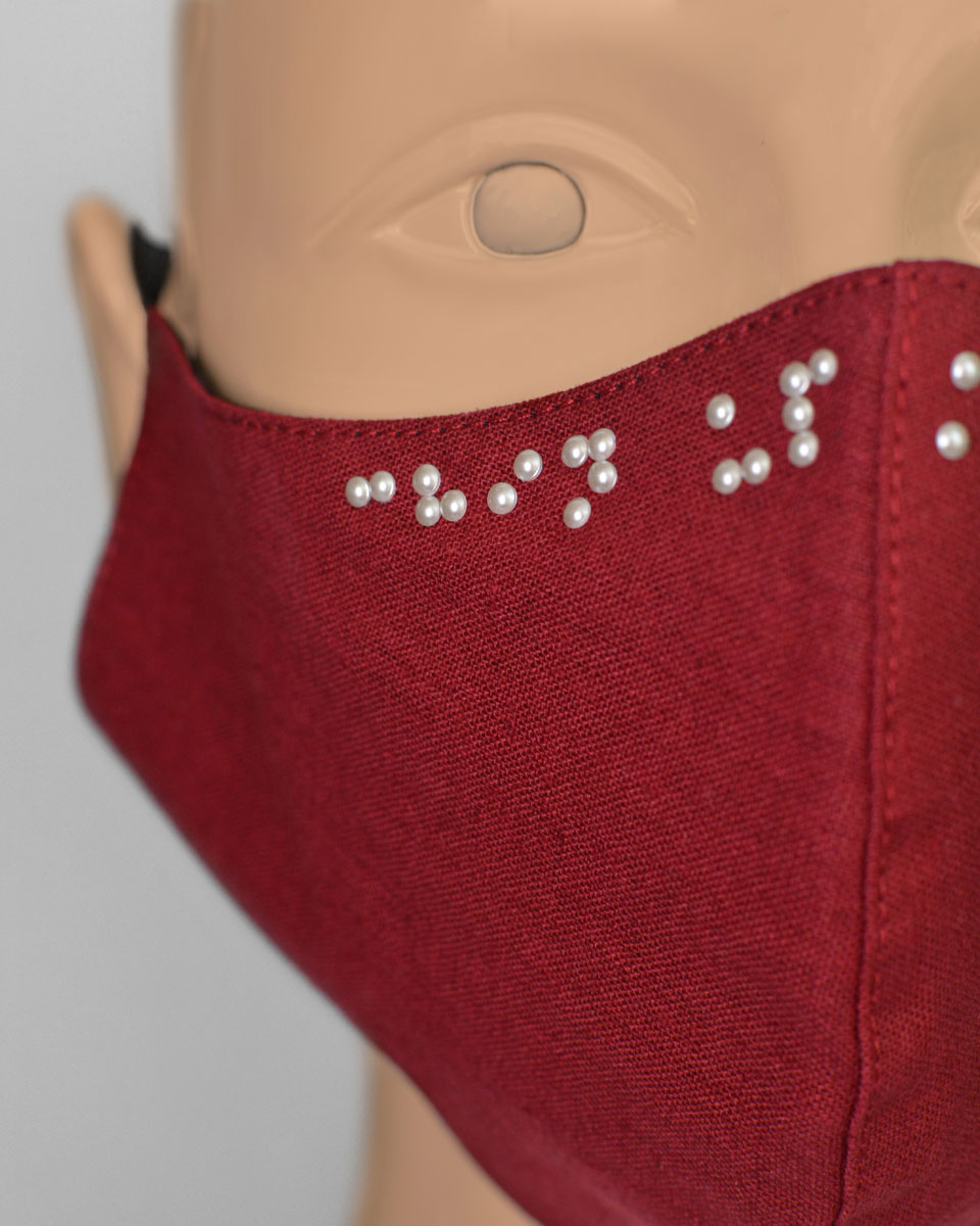 Mannequin head with a red face mask with braille crystals reading Chin Up Mask On