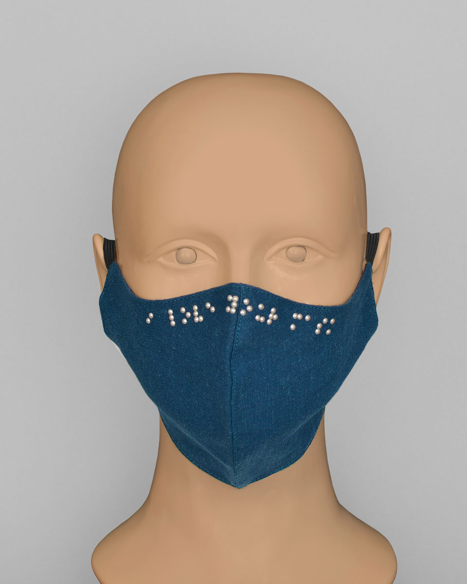 Mannequin head wearing a blue face mask with pearls spelling out "I love your mask" in Braille