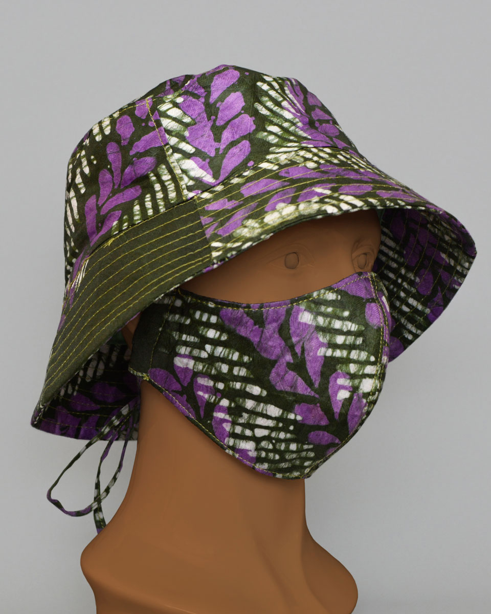 Side view of a mannequin head wearing a green, white and purple patterned hat and mask