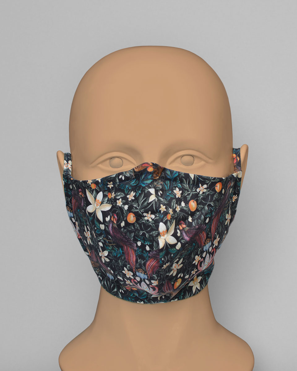 Mannequin head wearing a black mask with a fruit, floral and bird print