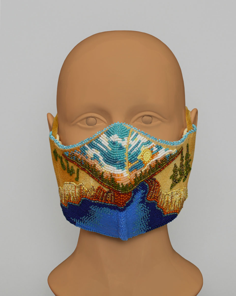 Mannequin head wearing a leather mask with a beaded landscape