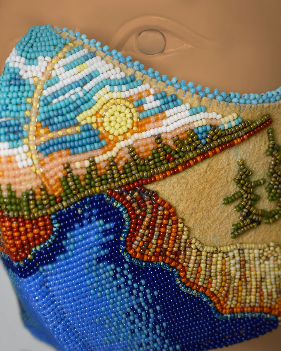 Close up of the beaded landscape with a sun, river and trees