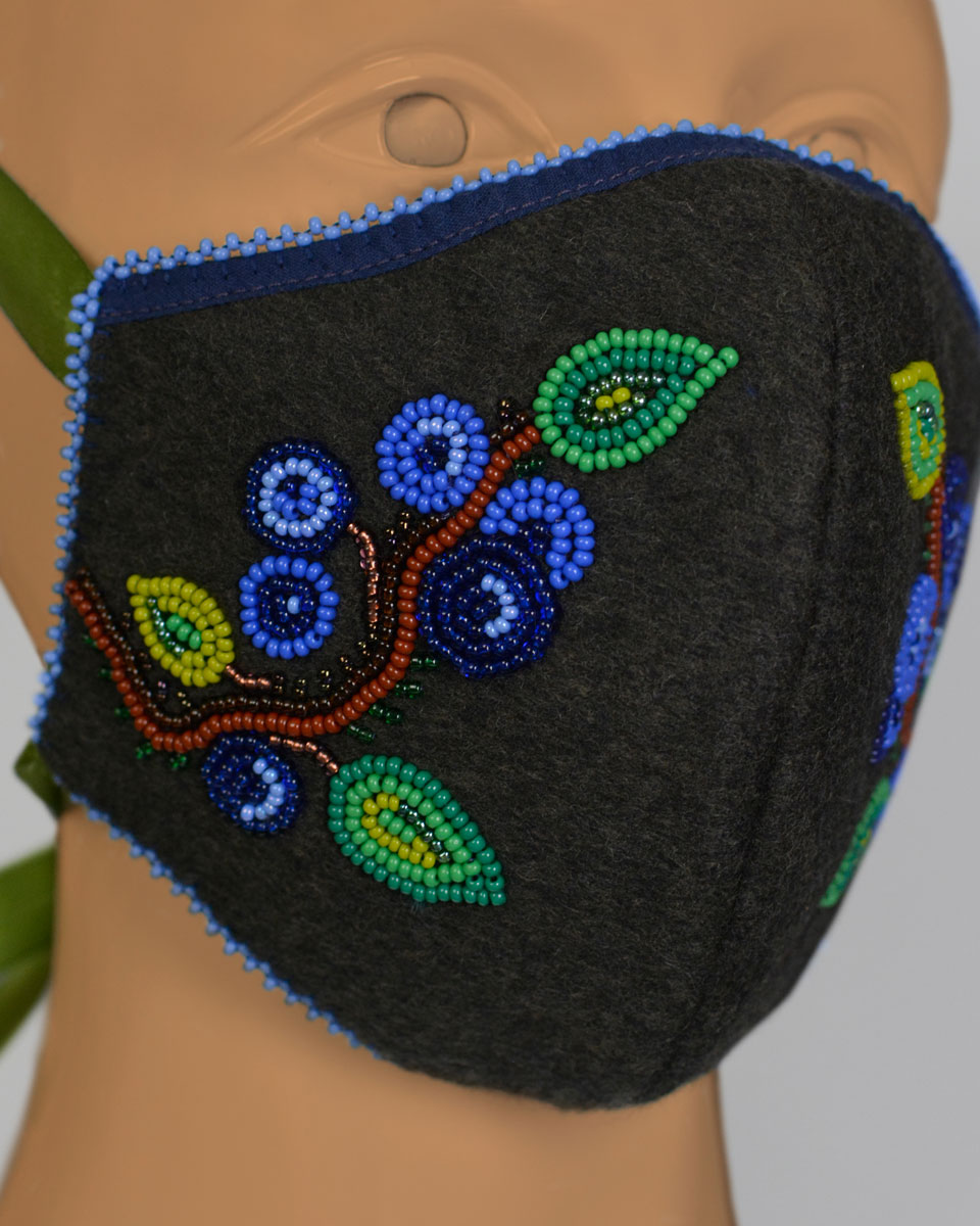 Close up of a mannequin head wearing a blue face mask with a beaded blueberry design