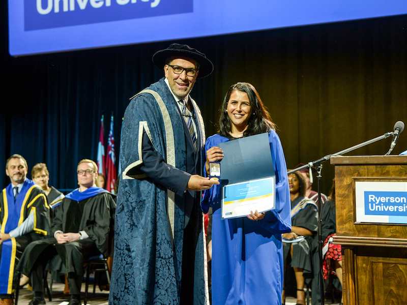 Annita Velasque Moreira on convocation stage, receiving the Ryerson Gold Medal and the Board of Governors Student Leadership Award and Medal.