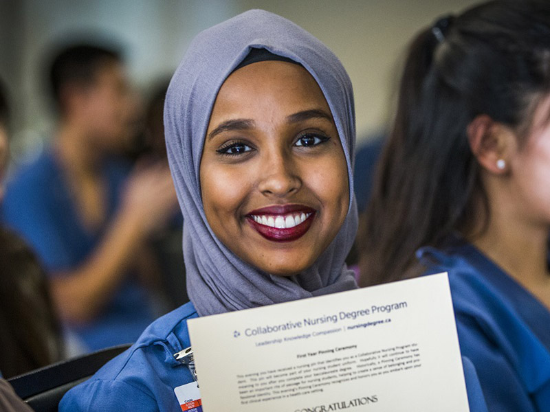 smiling student holding up certificate for nursing