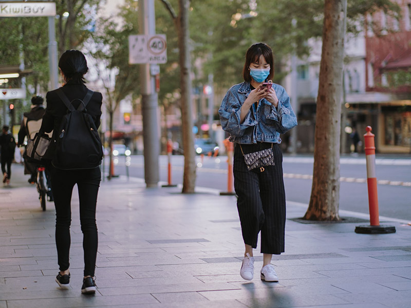 person with mask walking on city street
