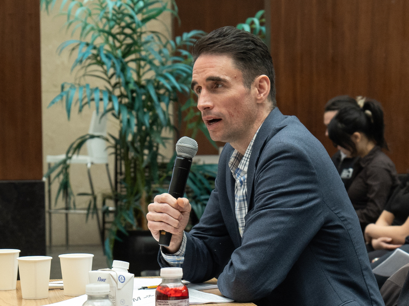 Professor Matthias Sweet at a judge's panel, speaking into a microphone