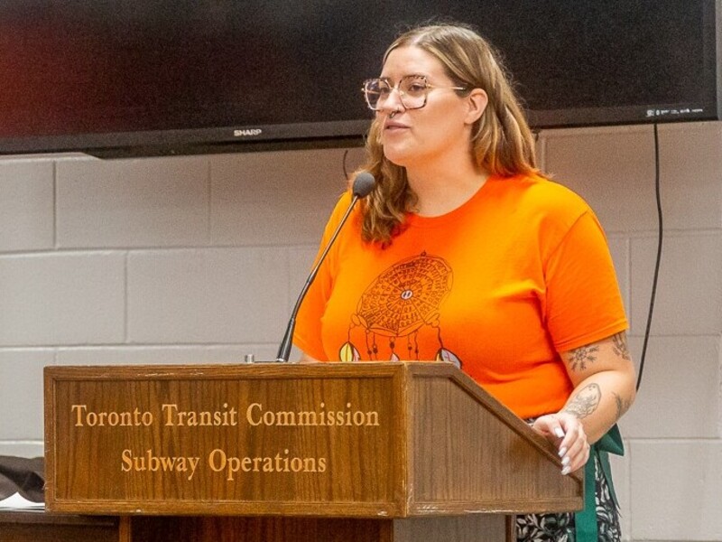 Jessica DeWit speaks from a podium that's inscribed with "Toronto Transit Commission Subway Operations"