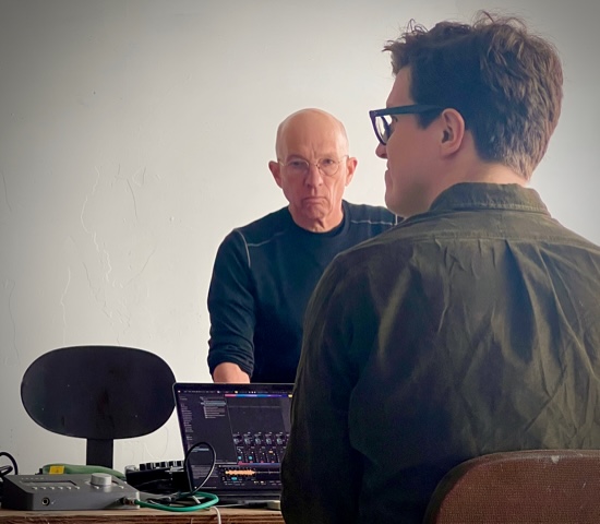 Two workshop participants operate computers and sound equipment.