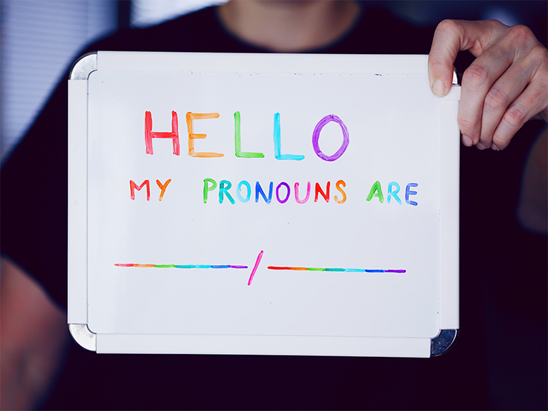 Person holding up sign reading "Hello my pronouns are"