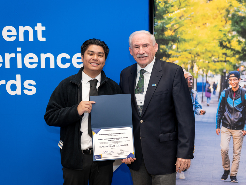 Clarence Carl Magsombol smiles, holding his certificate with Dennis Mock.