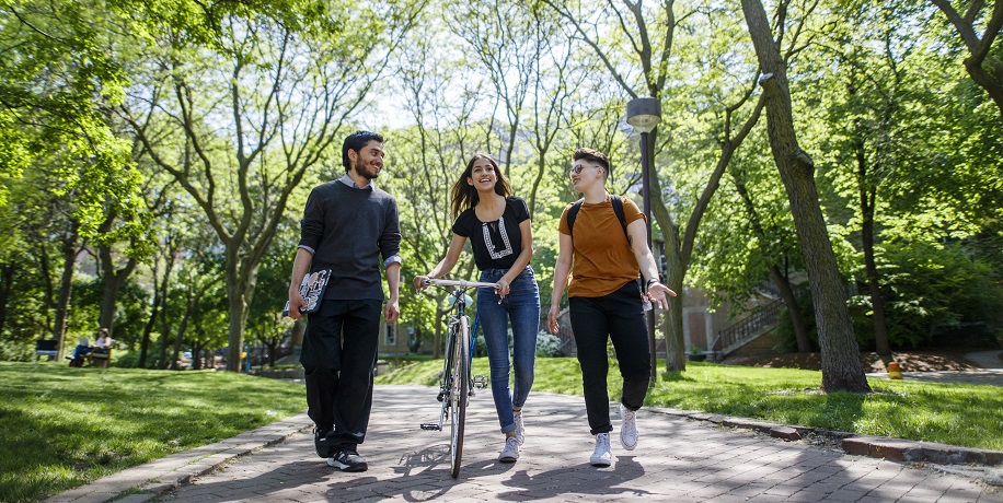 3 students walking and talking in a park trail