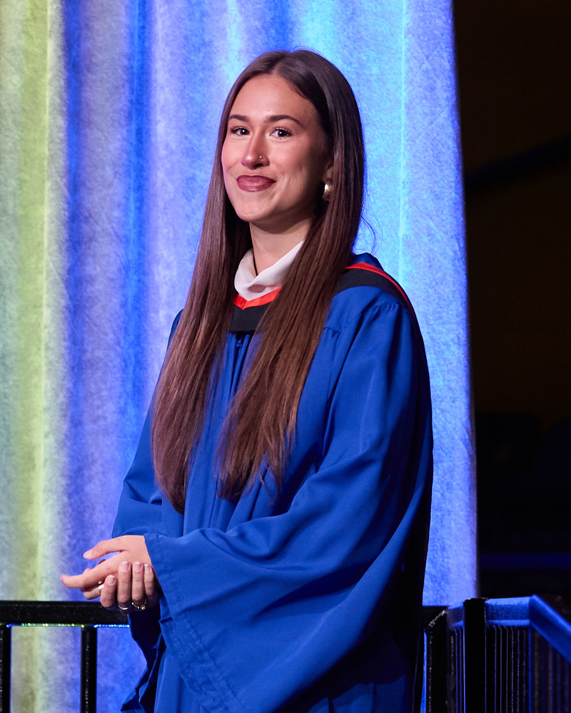 Kayla Longland in graduation gown smiles at convocation