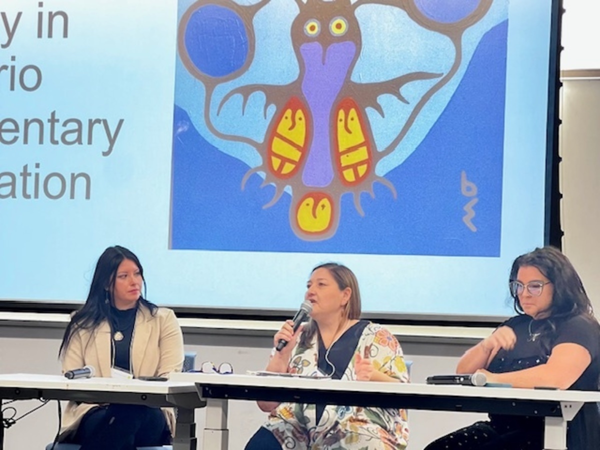 Three female panellists speak with a slide of Indigenous art behind them at the Enhancing Equity in Ontario Elementary Education Symposium