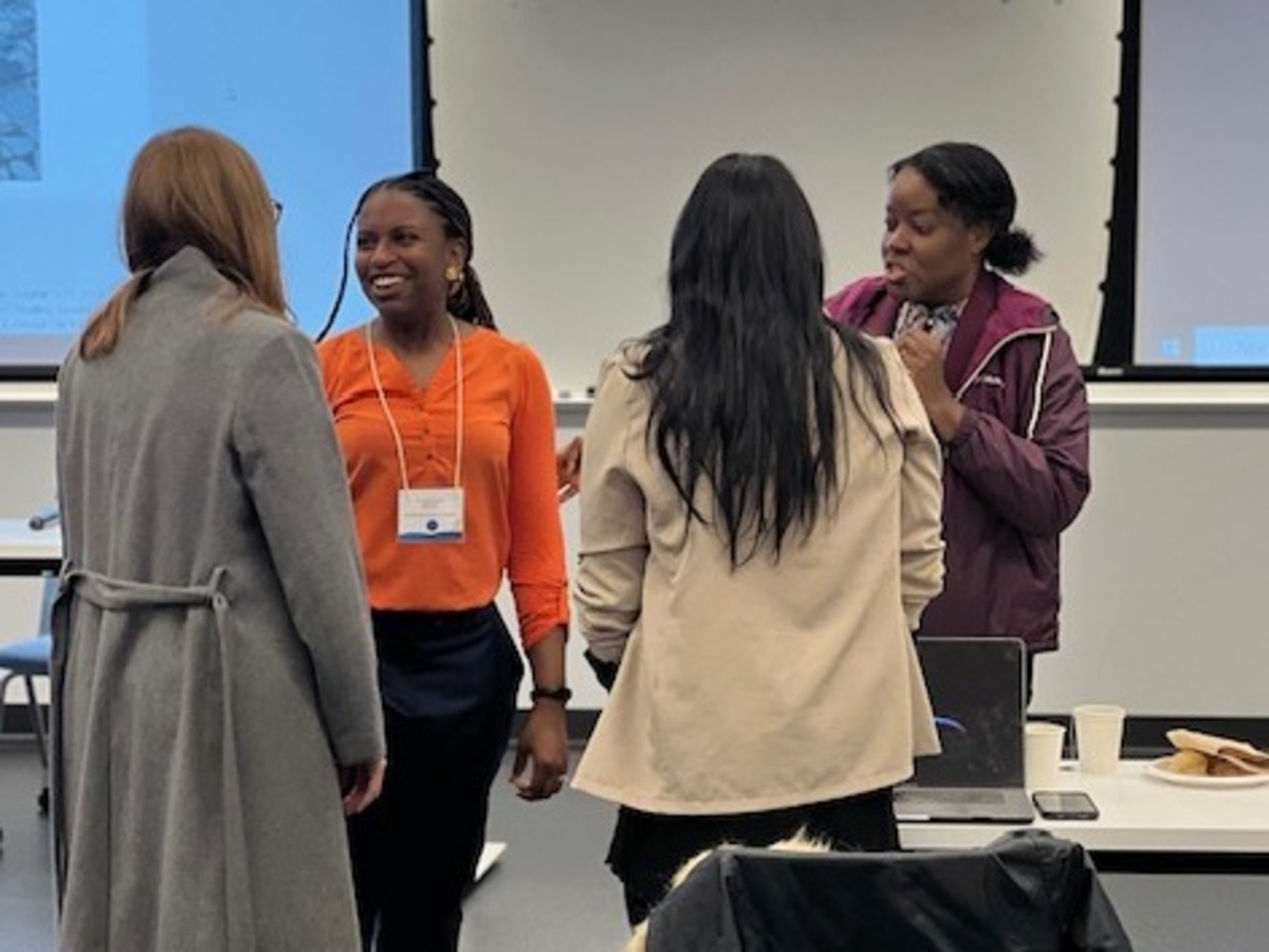 Four female attendees mingle and chat at the Enhancing Equity in Ontario Elementary Education Symposium