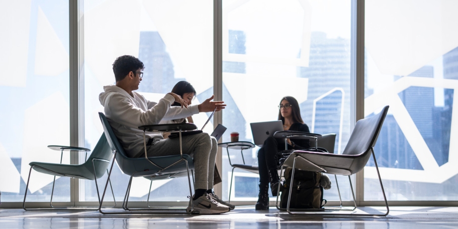 Three students studying together beside the windows of the Student Learning Centre